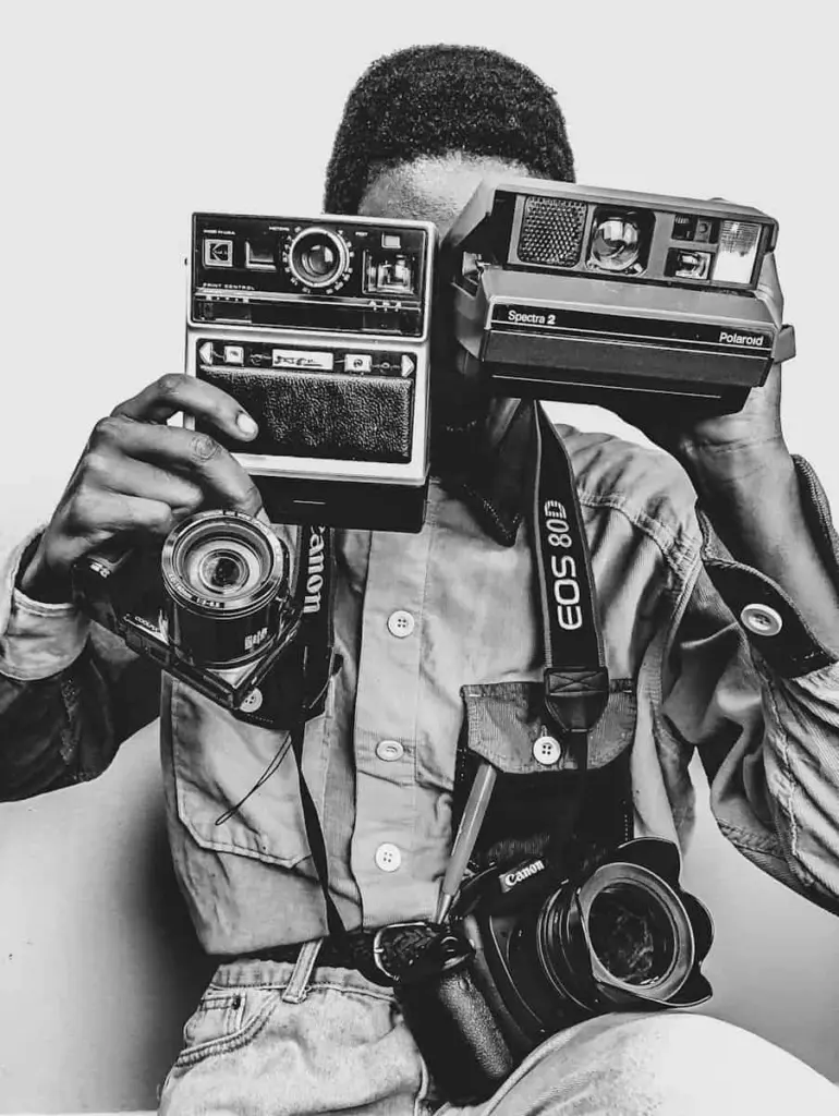 Un photographe derrière plusieurs appareils, en noir et blanc