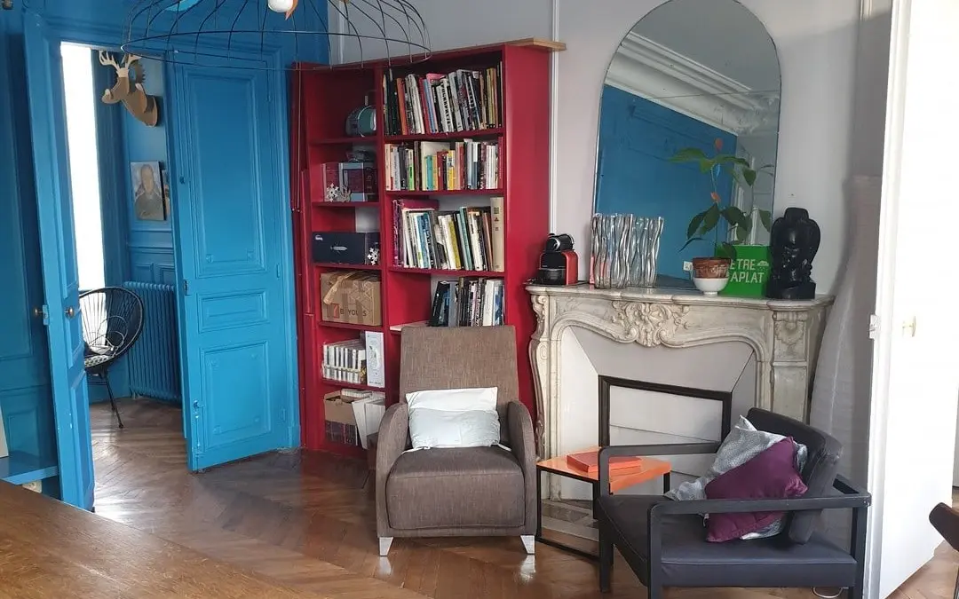 Le salon de l’agence, rue Greneta : portes bleues, bibliothèque rouge, cheminée en marbre et parquet en point de Hongrie